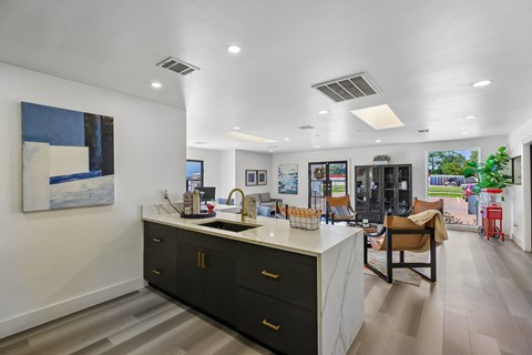 A modern kitchen with a large island and a painting on the wall.
