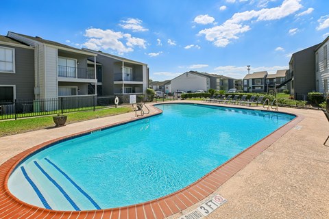 A swimming pool in a residential area with apartment buildings in the background.