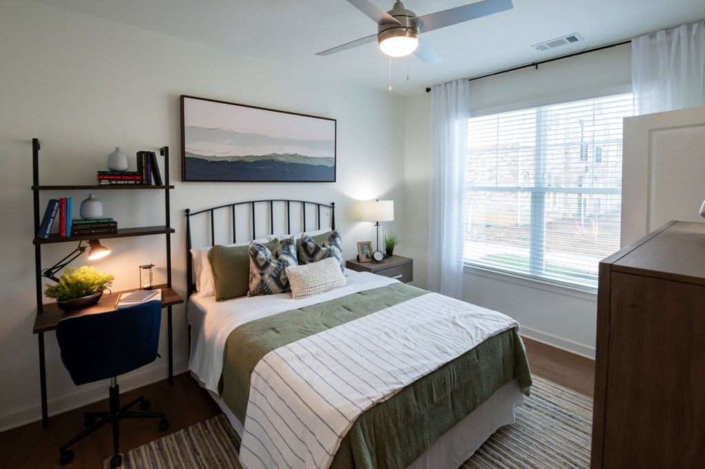 A bedroom with a bed, desk, and chair.