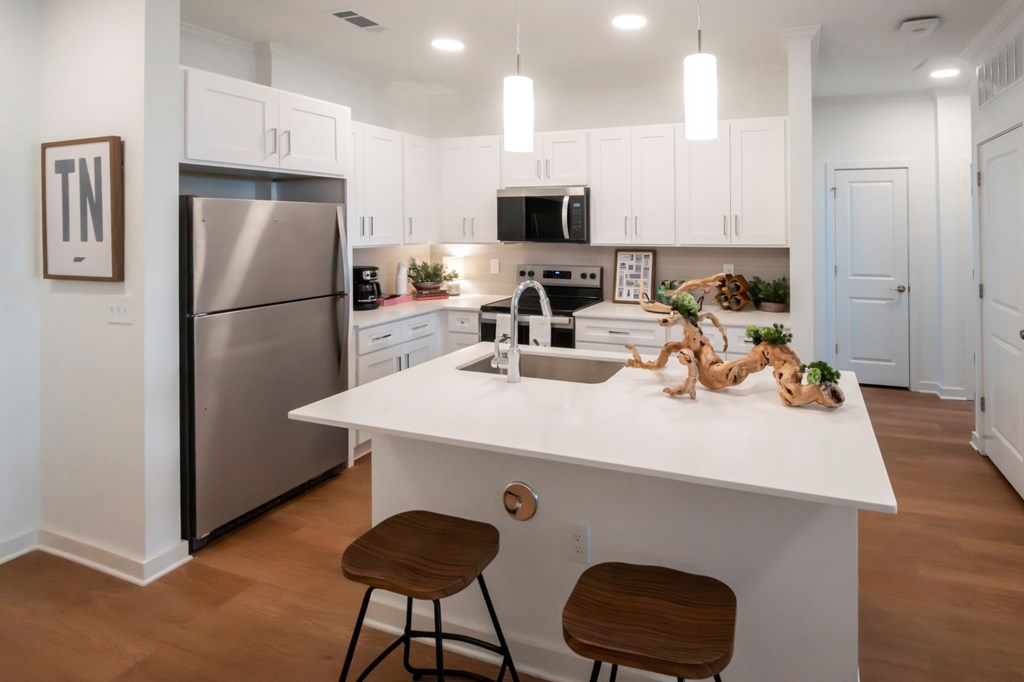 A modern kitchen with a white island and stainless steel appliances.
