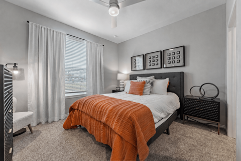 A bedroom with a bed covered in an orange blanket.