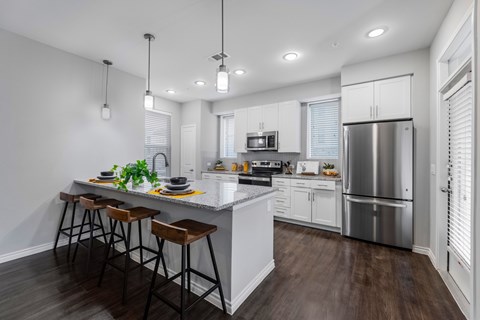 A modern kitchen with a bar area and stools.