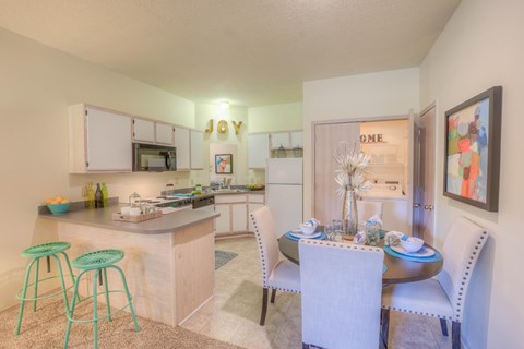 A kitchen with a bar stool and a dining table set for two.at Park at Forest Hill, Memphis, TN