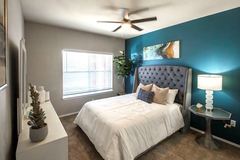 A bedroom with a white bed and a blue headboard. at Park at Forest Hill Apartments, Memphis