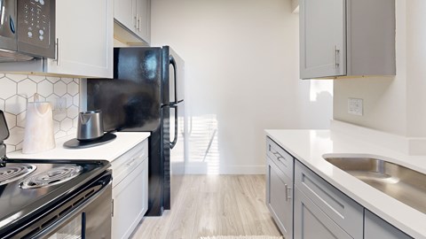 A modern kitchen with a black refrigerator and stove.