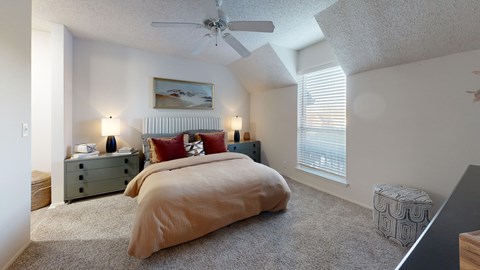 A bedroom with a bed, nightstands, and a ceiling fan.