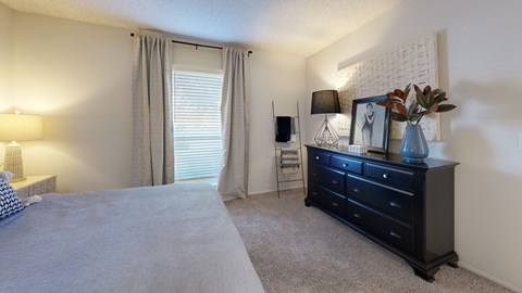 A bedroom with a bed, nightstand, and a painting on the wall.