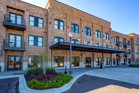 The Proviso building has a brick facade and a landscaped courtyard in front.