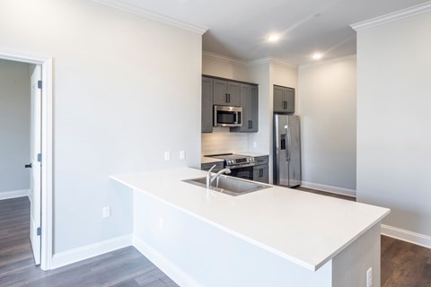 A kitchen with a white counter top and stainless steel appliances.