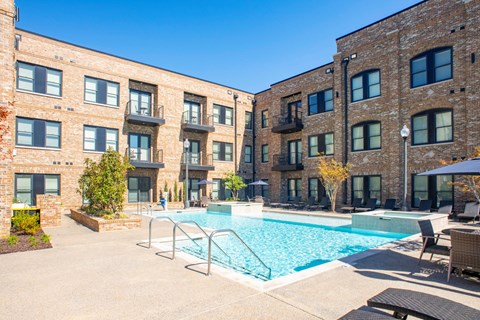 A swimming pool is surrounded by a patio area and chairs.