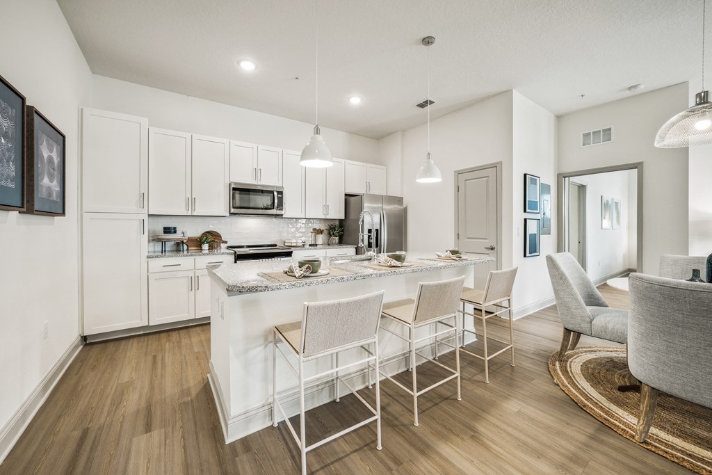 a kitchen with white cabinets and a large island with chairs