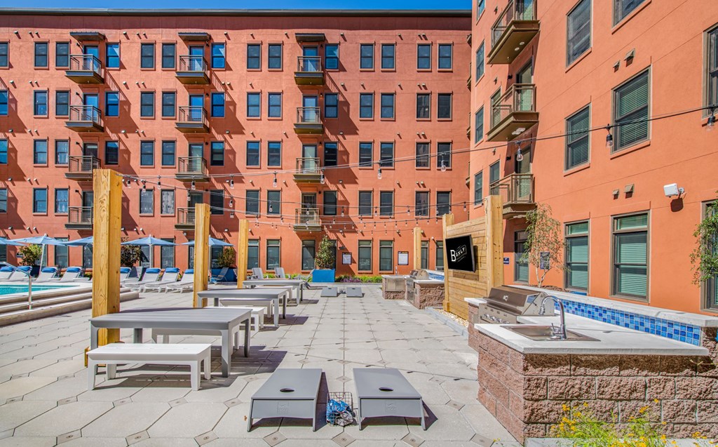an outdoor patio with tables and benches in front of an apartment building