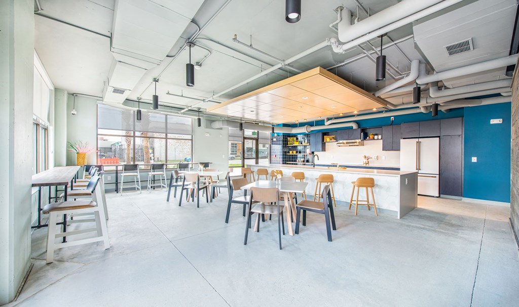 a large room with tables and chairs and a kitchen