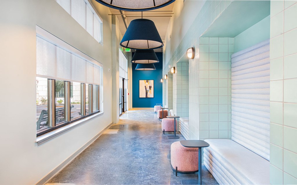 a hallway with benches and chairs and a row of windows