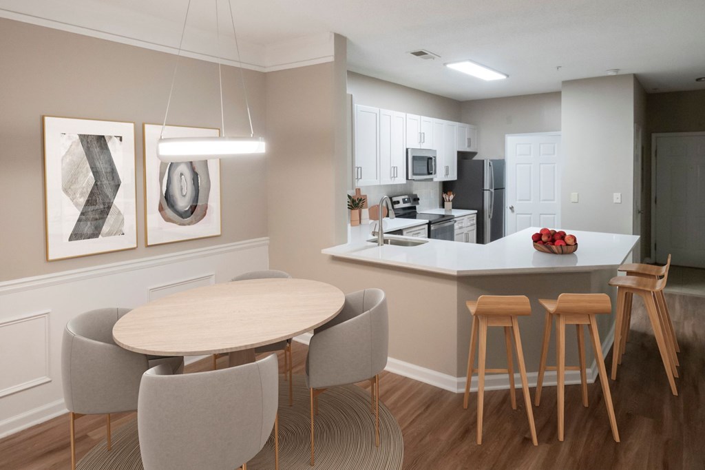 A kitchen with a table and chairs in the foreground and a refrigerator in the background.