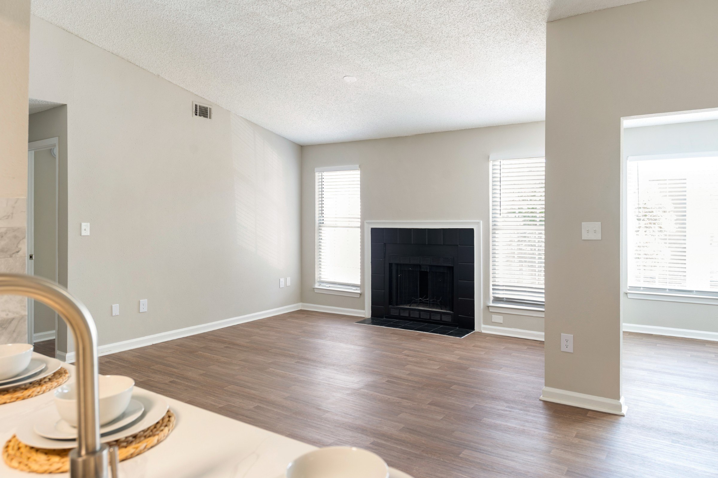 A modern living room with a fireplace and a dining table set for two.