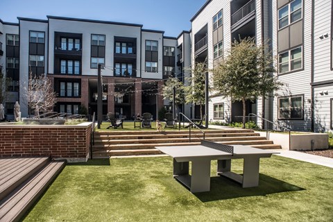 a patio with a table and benches in front of some buildings