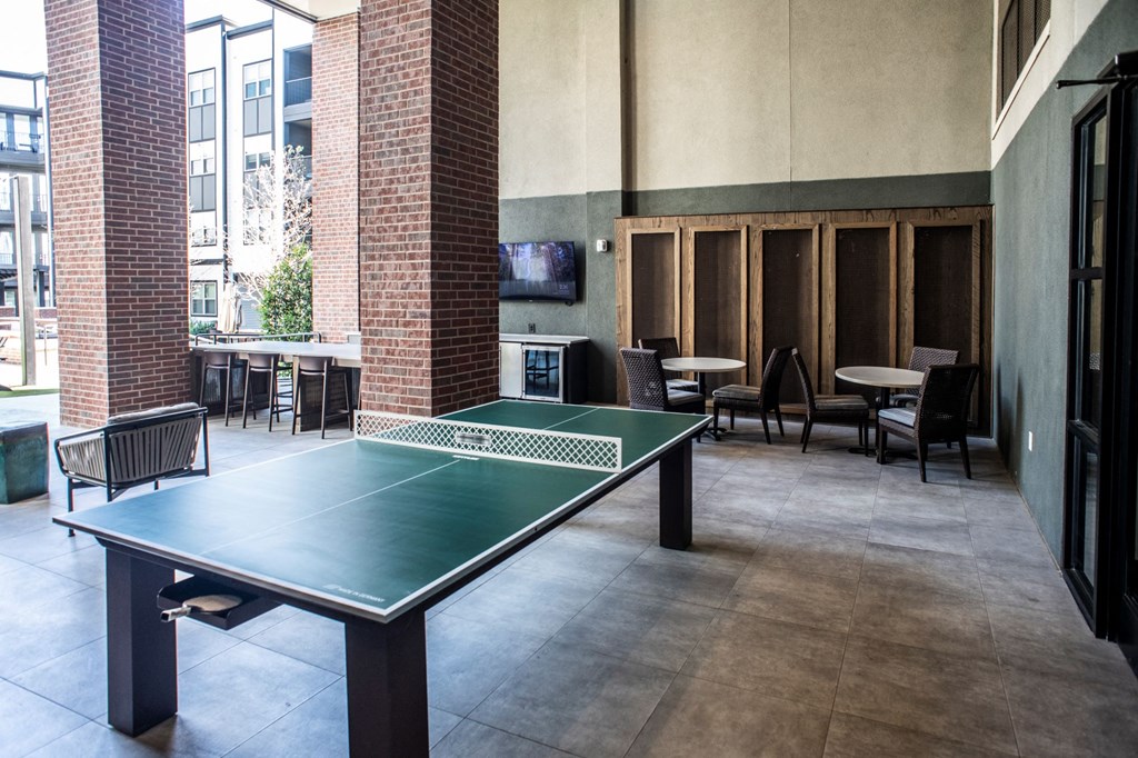 a ping pong table in a room with tables and chairs