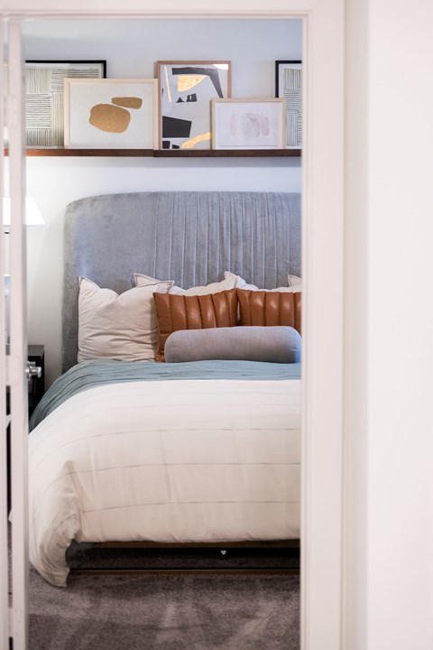a bedroom with a bed with pillows and pictures on the wall