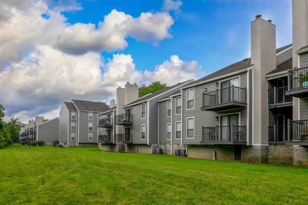 A row of modern apartment buildings with balconies and green lawns in front.
