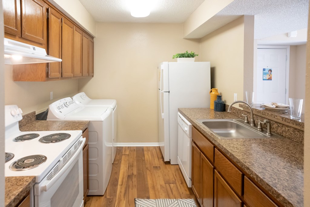 A kitchen with white appliances and wooden cabinets.