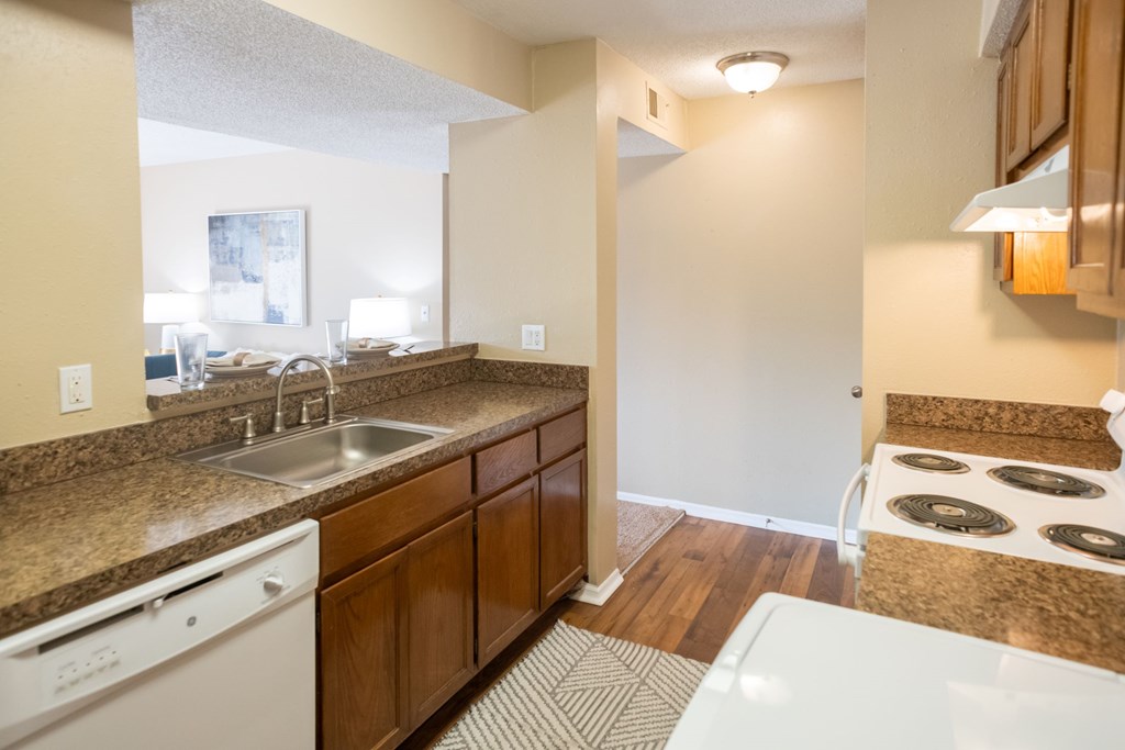 A kitchen with a white dishwasher and brown cabinets.