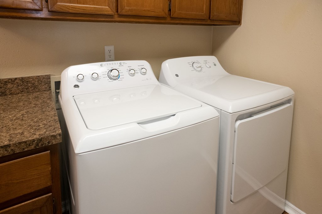 Two white front loading washing machines in a laundry room.