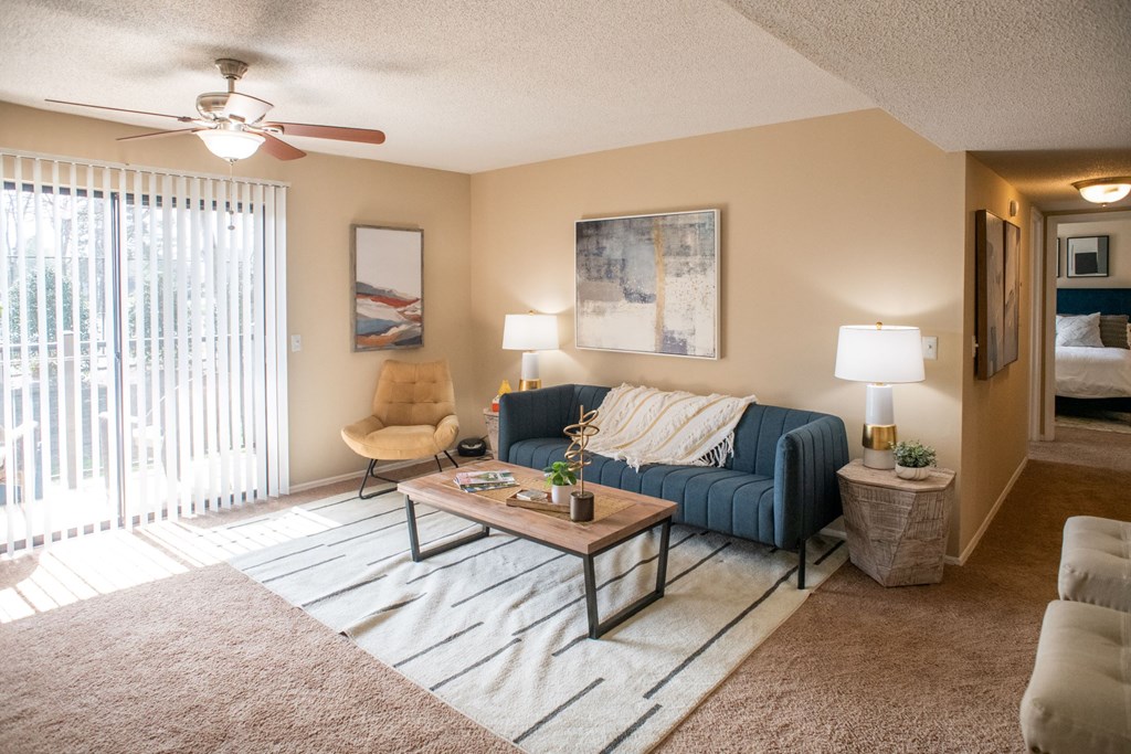A living room with a blue couch, a chair, a coffee table, and two lamps.