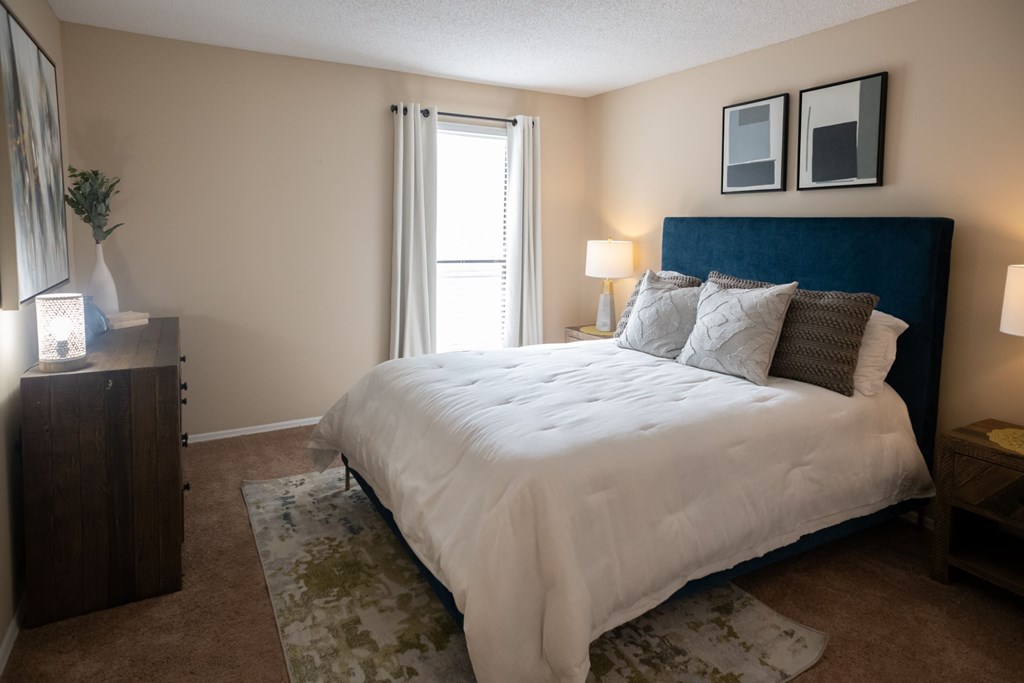 A bedroom with a large bed and a wooden dresser.