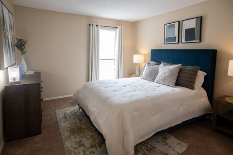 A bedroom with a large bed and a wooden dresser.