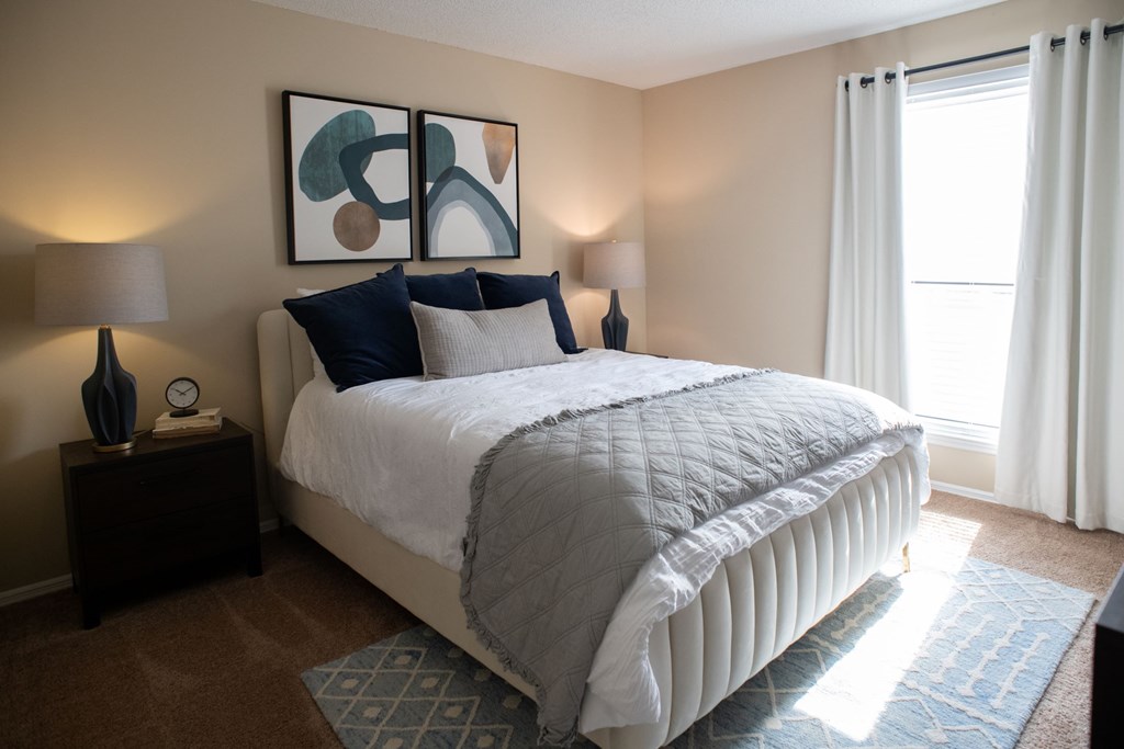 A bedroom with a large bed and a painting on the wall.