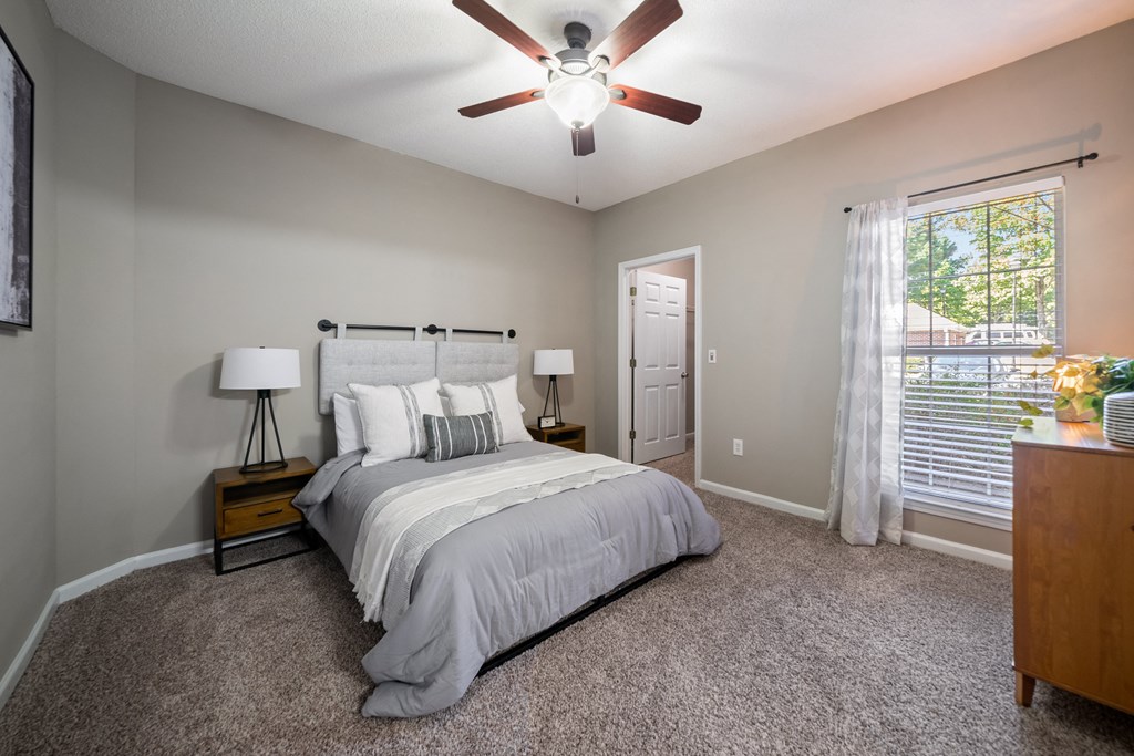 Secondary bedroom with ceiling fan and large window located at Sugarloaf Crossings Apartments in Lawrenceville, GA 30046
