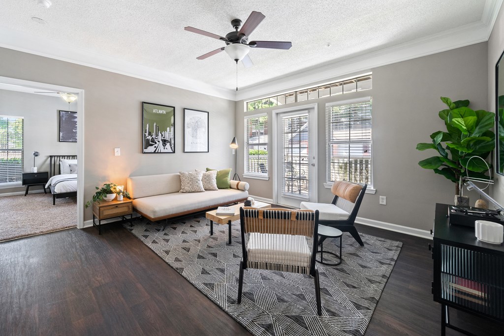 Spacious living room with patio door and large windows located at Sugarloaf Crossings Apartments in Lawrenceville, GA 30046
