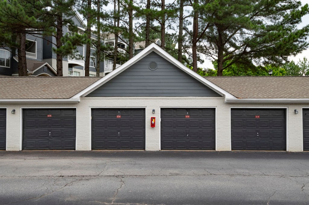 A building with a grey roof and white walls has five garage doors.