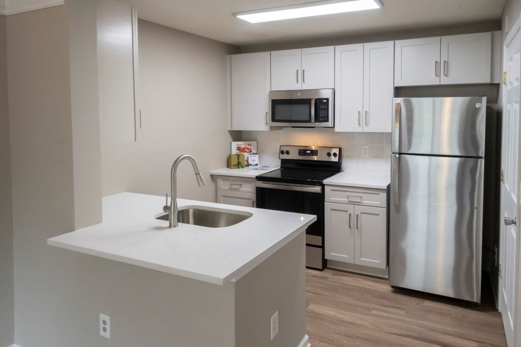 A kitchen with a stainless steel refrigerator, sink, and cabinets.