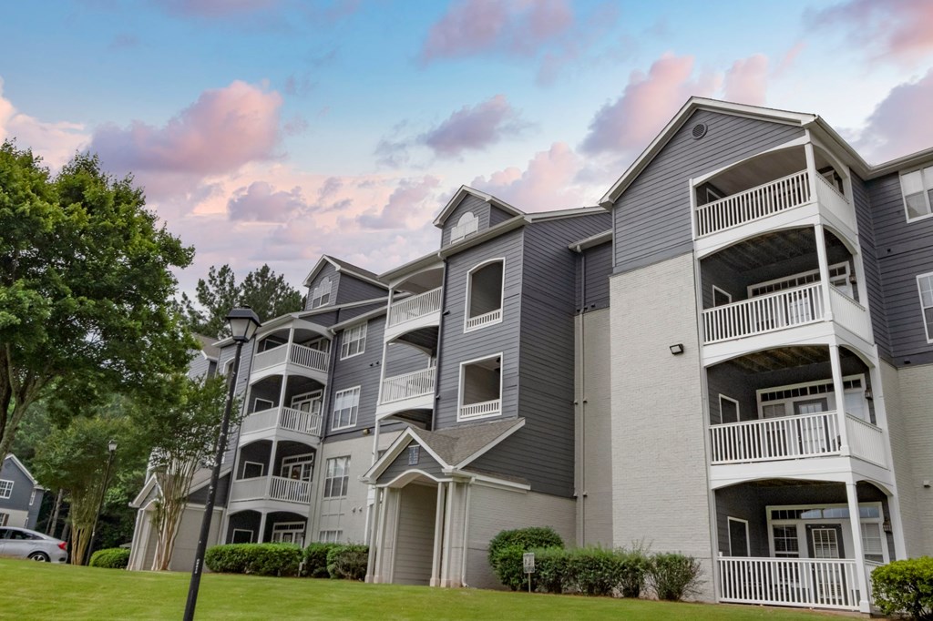 Apartment building with balconies and a car parked in front.