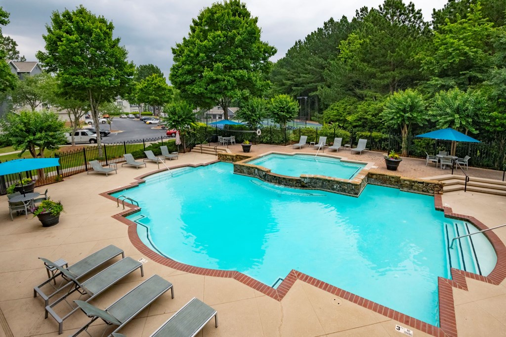 A large outdoor swimming pool surrounded by trees and lounge chairs.