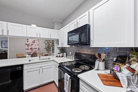 A kitchen with black appliances and white cabinets. at The Ambrose, Texas