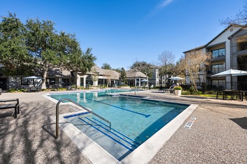 A swimming pool surrounded by trees and buildings. at The Ambrose, Houston, Texas