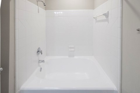 A white bathroom with a white tub and shower.
