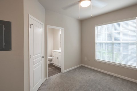 A well-lit, empty room with a toilet and sink visible through the open door.