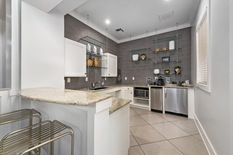 A kitchen with white cabinets and a marble countertop.