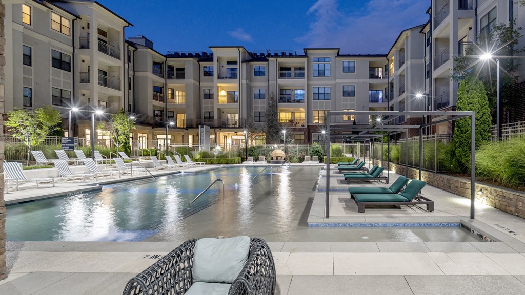 an apartment swimming pool with lounge chairs at night at The Hendrix, Georgia