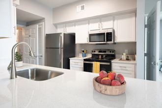 a kitchen with white cabinets and a white counter top with a bowl of fruit on it
