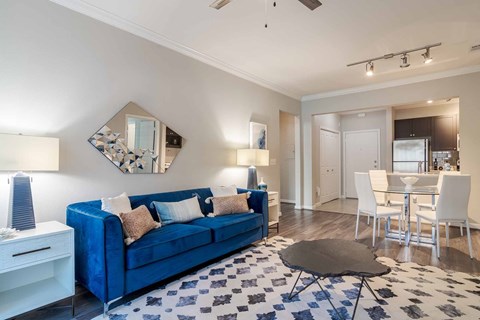 A blue couch sits in a living room with a black and white rug.