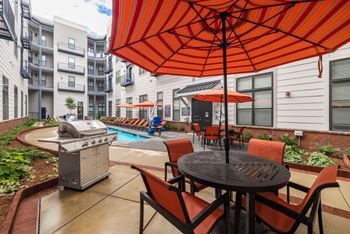 A patio with a table and chairs under an orange umbrella. at The Tennessee Brewery, Memphis, TN, 38103