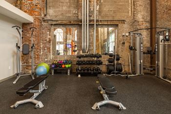 A gym with a variety of equipment including weights and a bench. at The Tennessee Brewery, Memphis