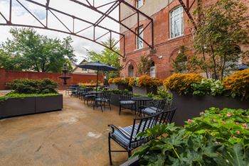 A patio with black chairs and a table is surrounded by plants and trees. at The Tennessee Brewery, Memphis