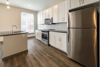 A modern kitchen with a stainless steel refrigerator and wooden floors. at The Tennessee Brewery, Memphis