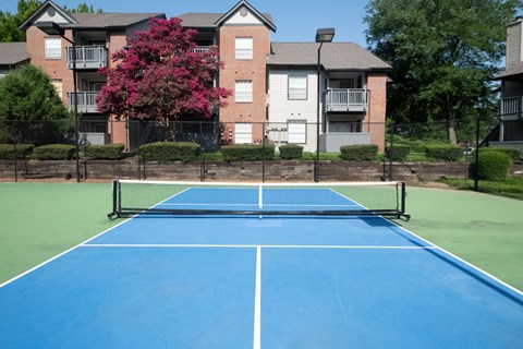 A blue tennis court in front of apartment buildings.